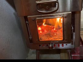 A wood stove with fire visible through the glass door at a property in Bovey Tracey