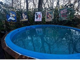 A hot tub with posters on a fence in an outdoor area at The Old Barn in Bovey Tracey