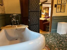 A bathroom with a bathtub and a room divider at The Old Barn in Bovey Tracey