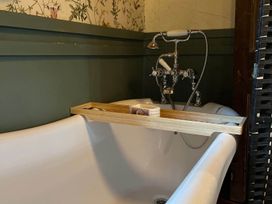 A bathtub with a wooden shelf and faucet in a bathroom at 