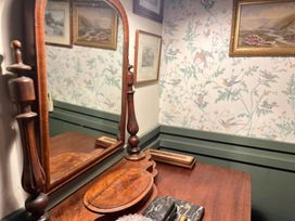 A wooden dressing table with a mirror and paintings on the wall at The Old Barn in Bovey Tracey