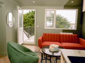 A living room with a red sofa, green armchair, and table at 1 Bedroom Apartment, sleeping 3 with balcony and pet friendly, Carbis Bay