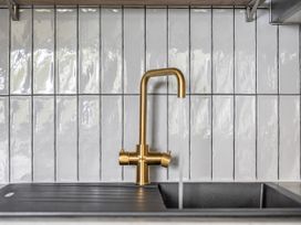 A kitchen sink with a gold faucet and tiled backsplash at 1 Bedroom Apartment, sleeping 3 with balcony and pet friendly, Carbis Bay