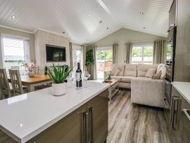 A living room with a sofa and dining area at 19 Pony Meadow near White Cross Bay
