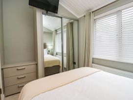 A bedroom with a bed and a wardrobe at 19 Pony Meadow near White Cross Bay