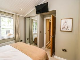 A bedroom with a bed and a television at 19 Pony Meadow White Cross Bay near Troutbeck Bridge