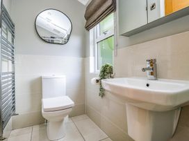 A bathroom with a toilet, sink, mirror, and towel radiator at 19 Pony Meadow White Cross Bay near Troutbeck Bridge