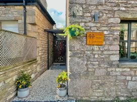 An entrance with stone walls and potted plants at Muddy Boots – La Petite Mews in Kirby Stephen