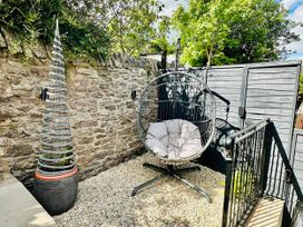 An outdoor area with a hanging chair and decorative tree at Muddy Boots – La Petite Mews in Kirby Stephen