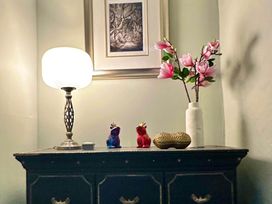 A living room with a lamp and a vase of flowers at Muddy Boots – Arcade Royale in Kirby Stephen