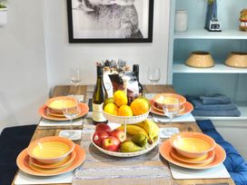 A dining table set with plates and a fruit bowl at Muddy Boots – Arcade Royale in Kirby Stephen