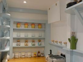A kitchen with shelves of mugs and glasses at Muddy Boots – Arcade Royale in Kirby Stephen