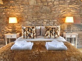A bedroom with a bed and stone wall at Muddy Boots – Arcade Royale in Kirby Stephen