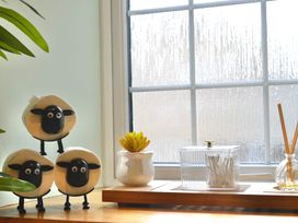 A kitchen window with sheep figurines and plants at Muddy Boots – Arcade Royale in Kirby Stephen