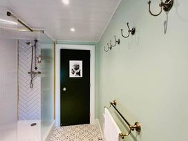 A bathroom with a shower and wall hooks at Muddy Boots – Arcade Royale in Kirby Stephen