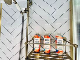 A bathroom with shampoo bottles on a shower rack at Muddy Boots – Arcade Royale in Kirby Stephen