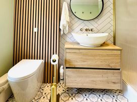 A bathroom with a toilet, sink, and mirror at Muddy Boots – Arcade Royale in Kirby Stephen