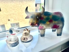 Figurines of a dog, cat, and cow on a windowsill