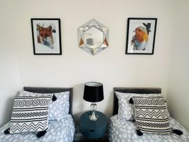 A bedroom with two beds, paintings, and a table lamp at Muddy Boots – Scarpa in Kirkby Stephen