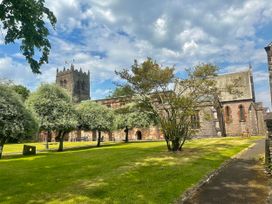 A church with a tower and trees in the surrounding grass area at Muddy Boots – Scarpa, Kirkby Stephen
