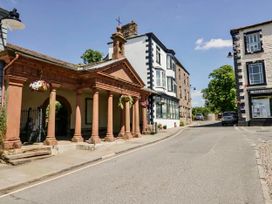 A street view with historic architecture and trees at Muddy Boots – Scarpa in Kirkby Stephen