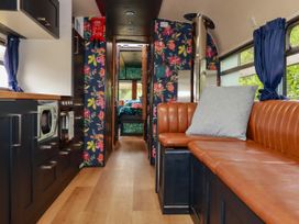A living room with a couch and kitchen area at Honey Bee Bus in Menheniot