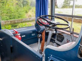 A bus interior with a steering wheel and dashboard at Honey Bee Bus Menheniot