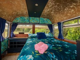 A bedroom with a bed and pillows in Honey Bee Bus Menheniot