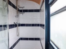 A shower with tiles and a window at Honey Bee Bus Menheniot