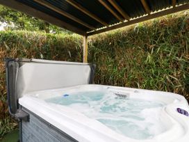 A hot tub under a shelter with surrounding foliage at Honey Bee Bus Menheniot