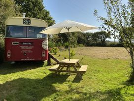 An outdoor area with a bus, table, and umbrella at Troopers Lodge in Glanvilles Wootton