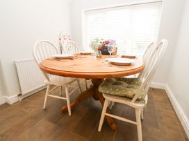 A dining room with a round wooden table and four chairs at Peewit Barn in Moreton-in-Marsh