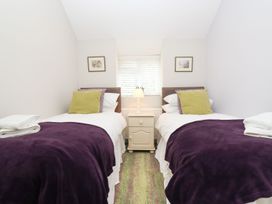 A bedroom with two beds and a bedside table at Peewit Barn in Moreton-in-Marsh