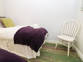 A bedroom with a bed and a chair at Peewit Barn in Moreton-in-Marsh