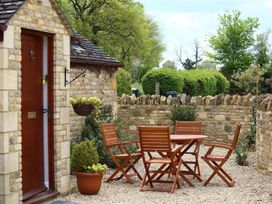 A garden with a stone wall and seating area at Peewit Barn in Moreton-in-Marsh