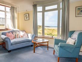 A living room with a sofa and table overlooking the beach at Chy-an-Lowena in Crantock