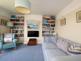 A living room with a sofa, bookshelf, and television at Chy-an-Lowena in Crantock