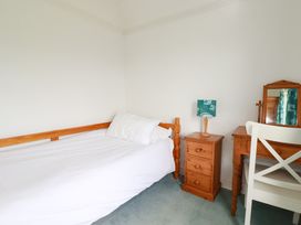 A bedroom with a bed, table, lamp, chair and mirror at Chy-an-Lowena in Crantock