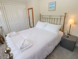 A bedroom with a bed, side table, lamp, and mirror at Hafan y Tyddyn 