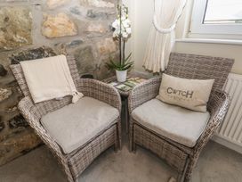 Two chairs with an orchid and a side table at Hafan y Tyddyn