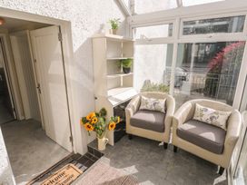 A conservatory with two chairs and a shelf at Hafan y Tyddyn