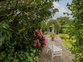 A garden with a pathway, flowers, and a bench at Bruckless Rest Fine Country Dining B&B Bruckless