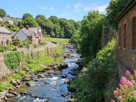 A stream with rocks and houses alongside it at Myrtle Cottage in Lynmouth