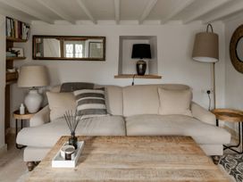 A living room with a sofa, coffee table, and shelves at Rose Cottage in Gweek