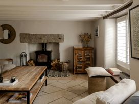 A living room with a fireplace and wooden table at Rose Cottage in Gweek