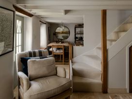 A living room with an armchair and dining table at Rose Cottage in Gweek