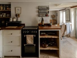 A kitchen with a cooking range and storage shelves at Rose Cottage in Gweek