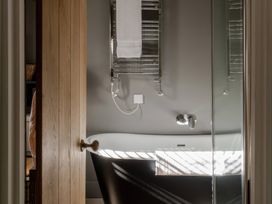 A bathroom with a bathtub and towel rail at Rose Cottage in Gweek