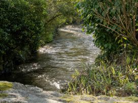 A flowing river with plants and trees at Rose Cottage in Gweek