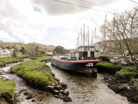 A boat on a river with grass and trees at Rose Cottage in Gweek
